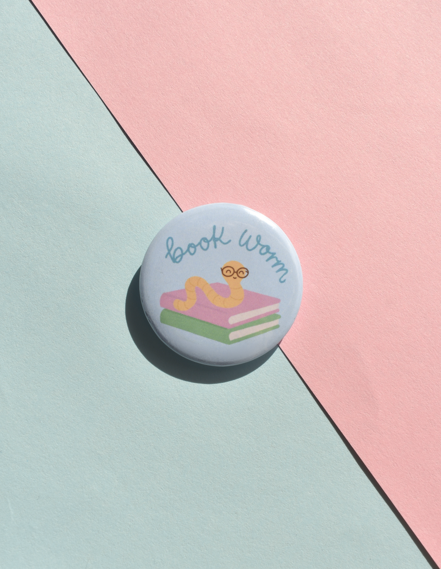 Button badge with 'Book Worm' text and illustrations on a pastel background