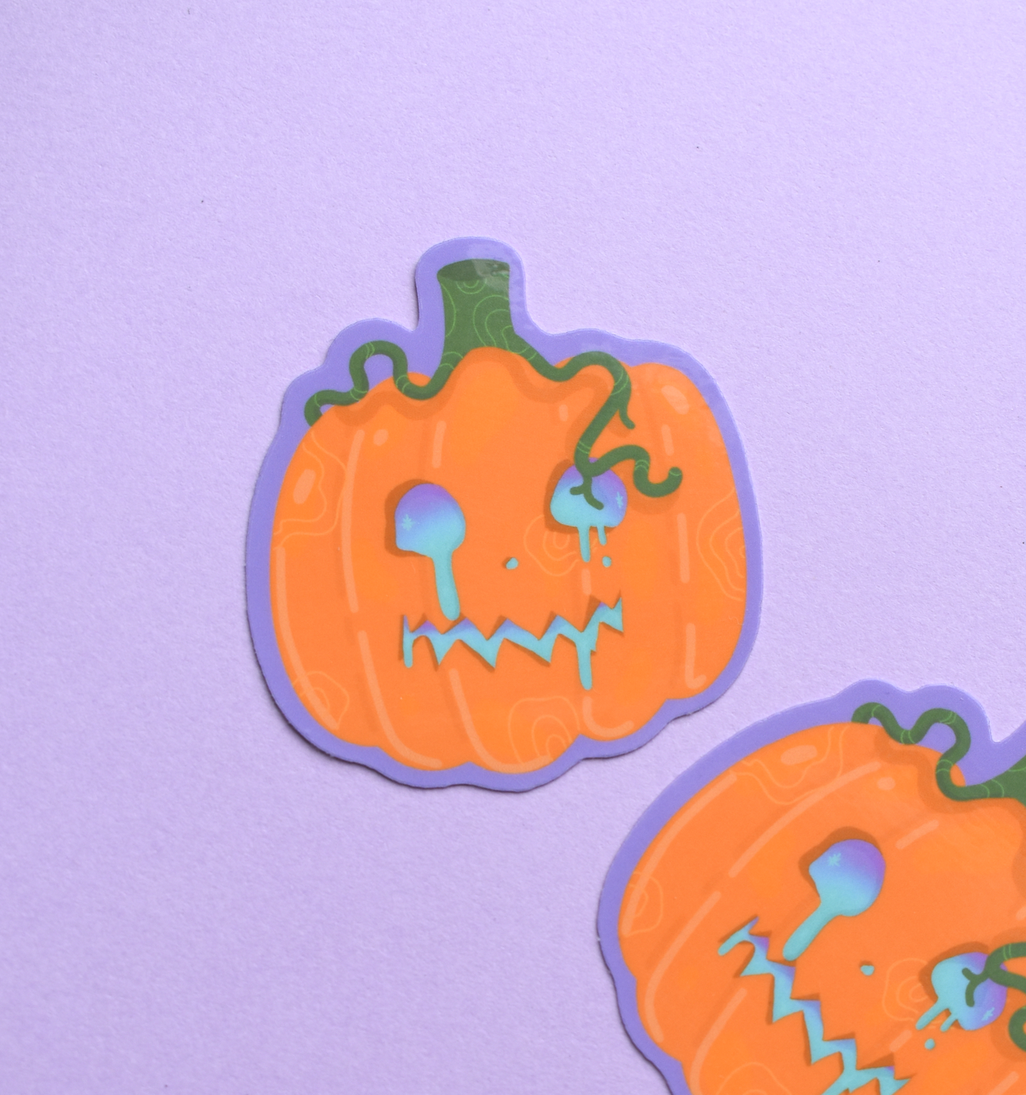 Two pumpkin-shaped stickers with faces on a purple background