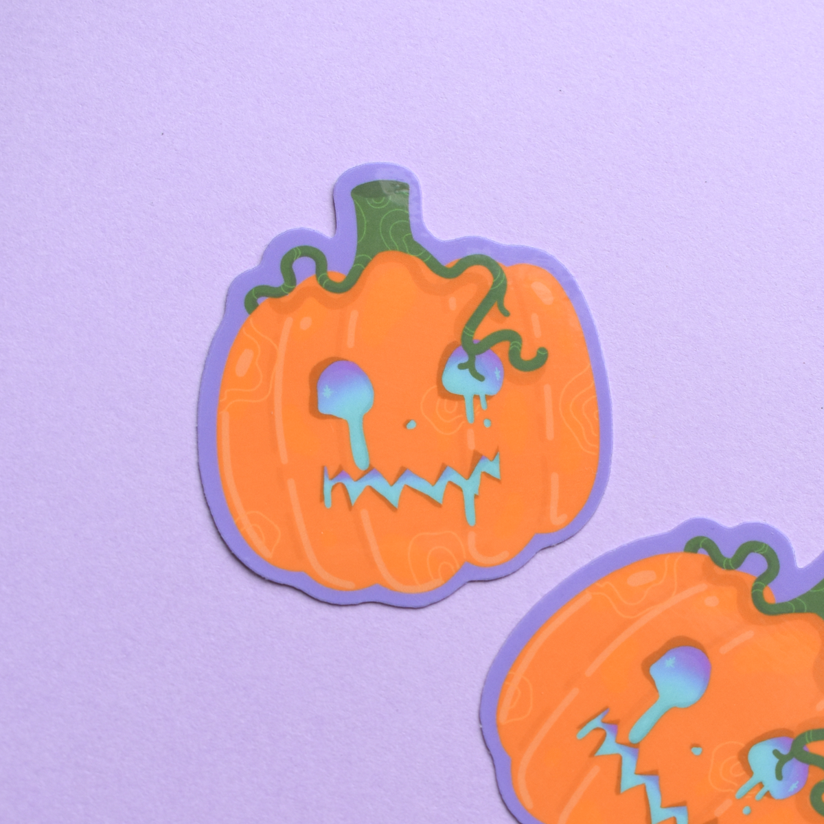 Two pumpkin-shaped stickers with faces on a purple background