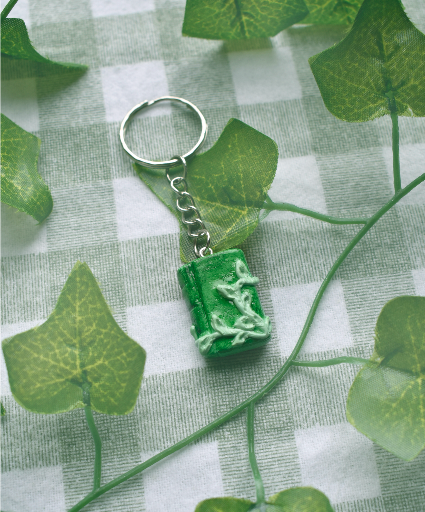 Green keychain with a leaf design on a green and white checkered background