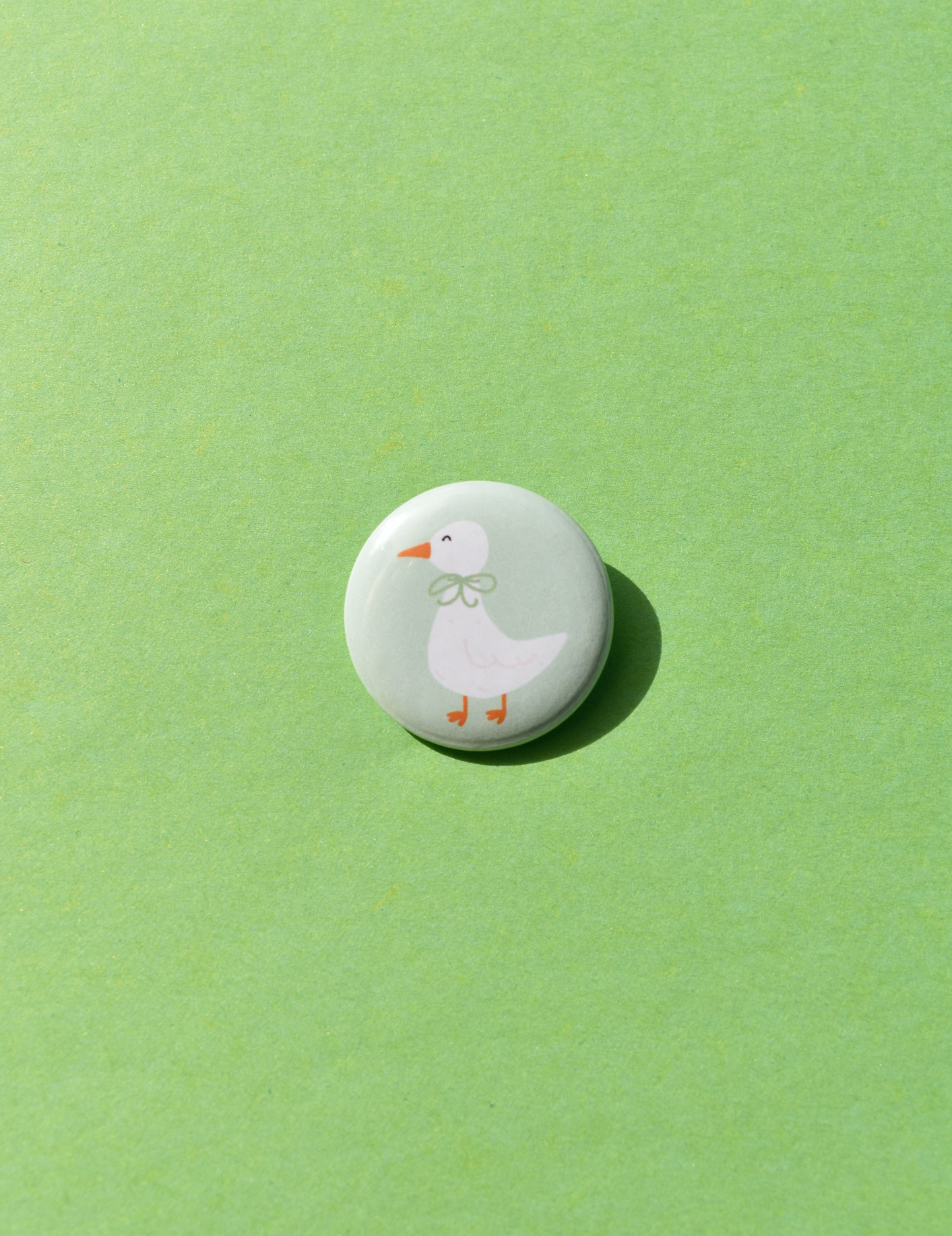 Round button with a cartoon duck design on a green background