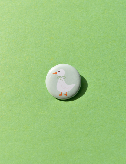 Round button with a cartoon duck design on a green background