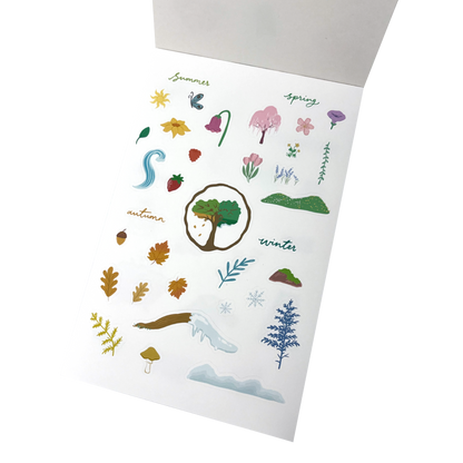 A matte white vinyl sticker sheet featuring seasonal illustrations for summer, spring, autumn, and winter.