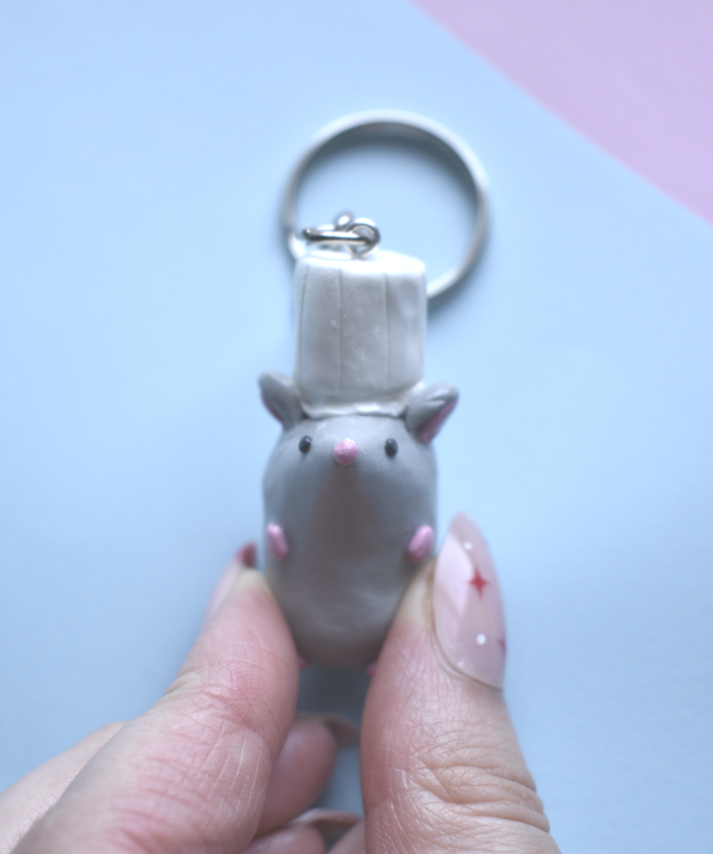 Keychain shaped like a mouse held by a hand against a light blue background