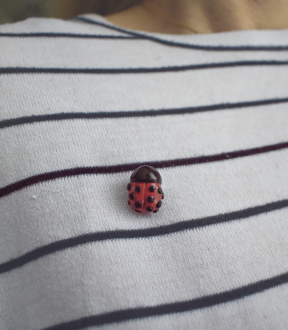 Small ladybug pin on a white shirt with black stripes