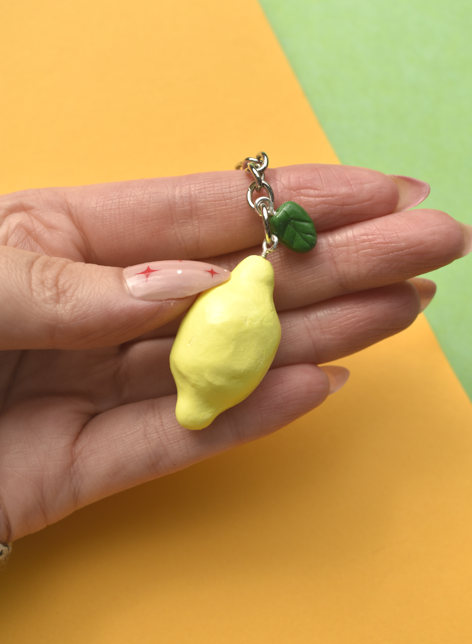 Hand holding a lemon-shaped keychain against a colorful background