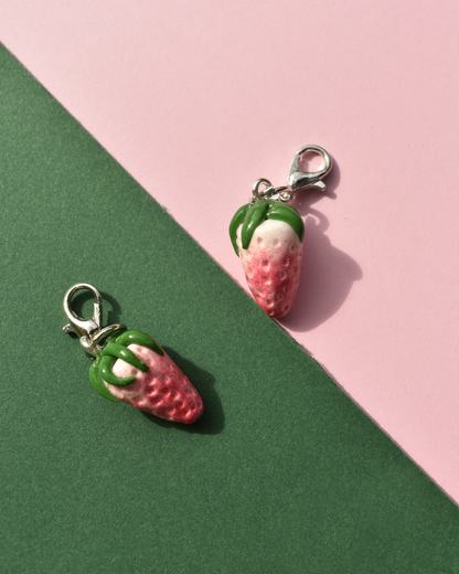 Two strawberry-shaped charms on a pink and green background