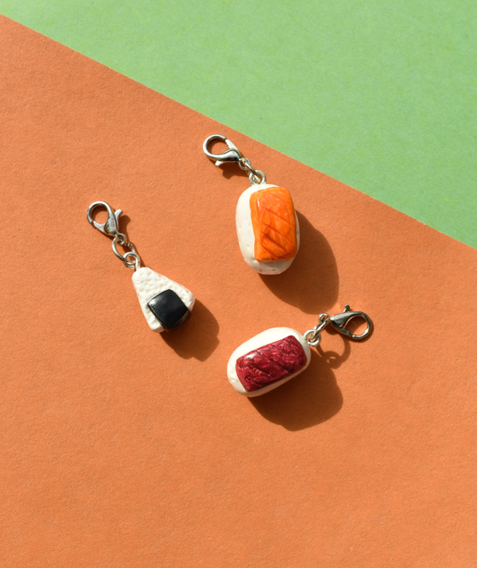 Three food-themed sushi charms on a colorful background