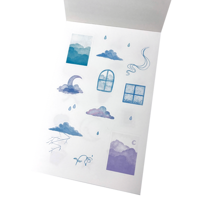 A matte white vinyl sticker sheet of watercolour-style cloud and sky illustrations in blue and purple tones.