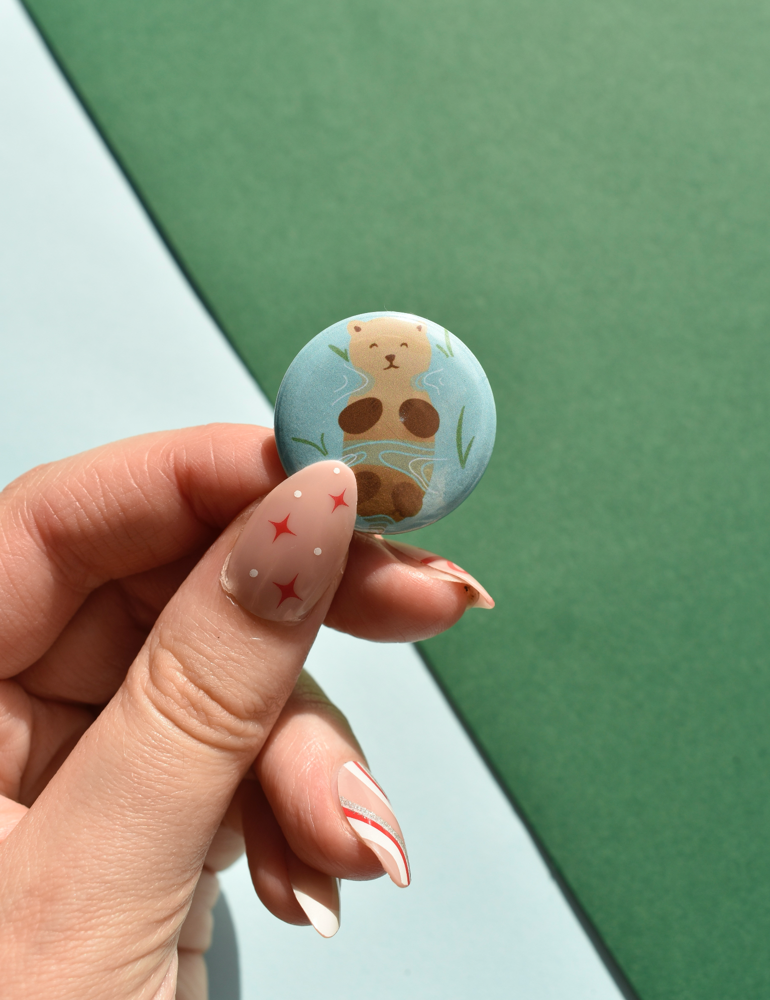 Button with bear design held by a hand against a green and white background