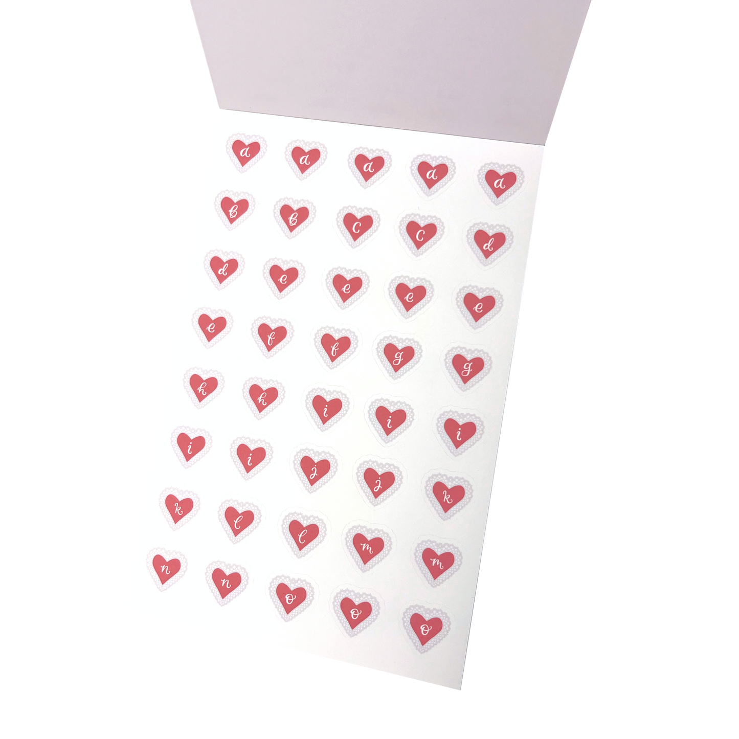 A sheet of small heart-shaped stickers with the letters a to o printed inside each heart, arranged on a matte white vinyl sticker sheet