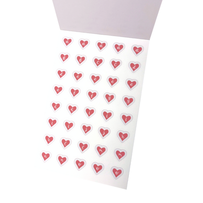 A sheet of small heart-shaped stickers with the letters a to o printed inside each heart, arranged on a matte white vinyl sticker sheet