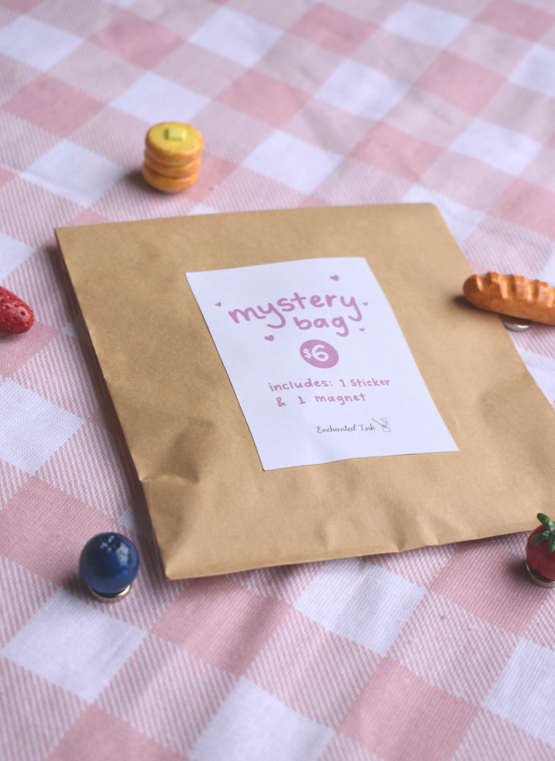 Kraft paper bag labeled 'mystery bag' on a checkered tablecloth with small food magnets around.