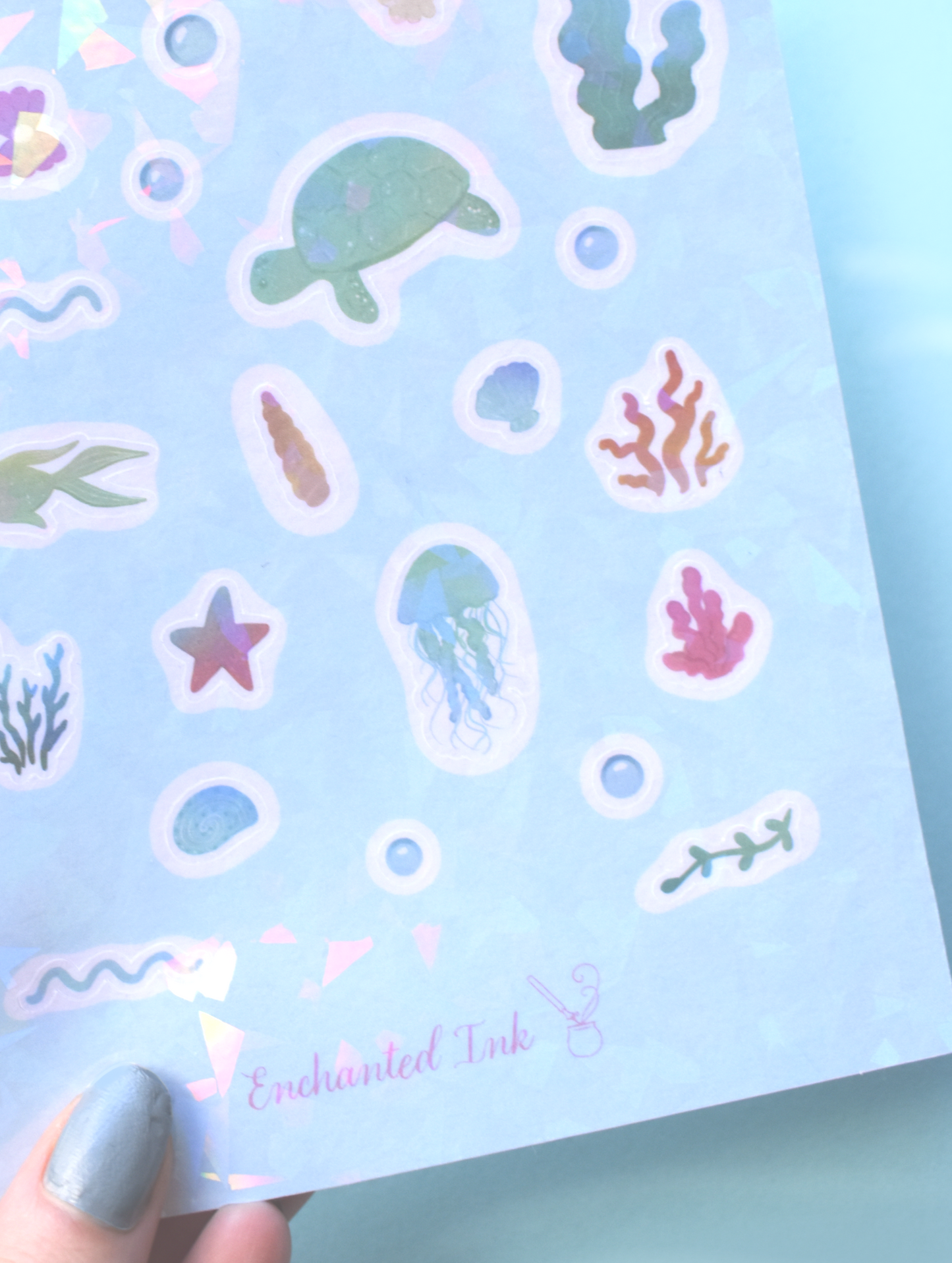 Sheet of ocean-themed stickers with sea creatures on a light blue background, held by a hand.