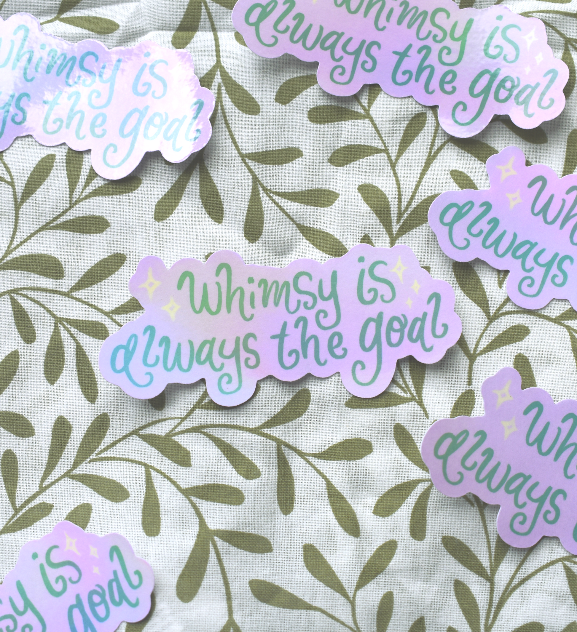 Detailed view of hand-lettered holographic sticker catching light in rainbow colours