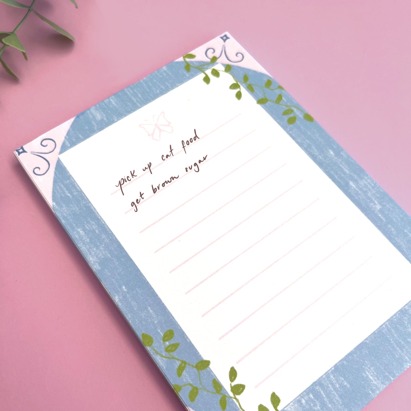 Close-up of enchanted butterfly notepad showing hand-drawn butterfly illustration and vine border