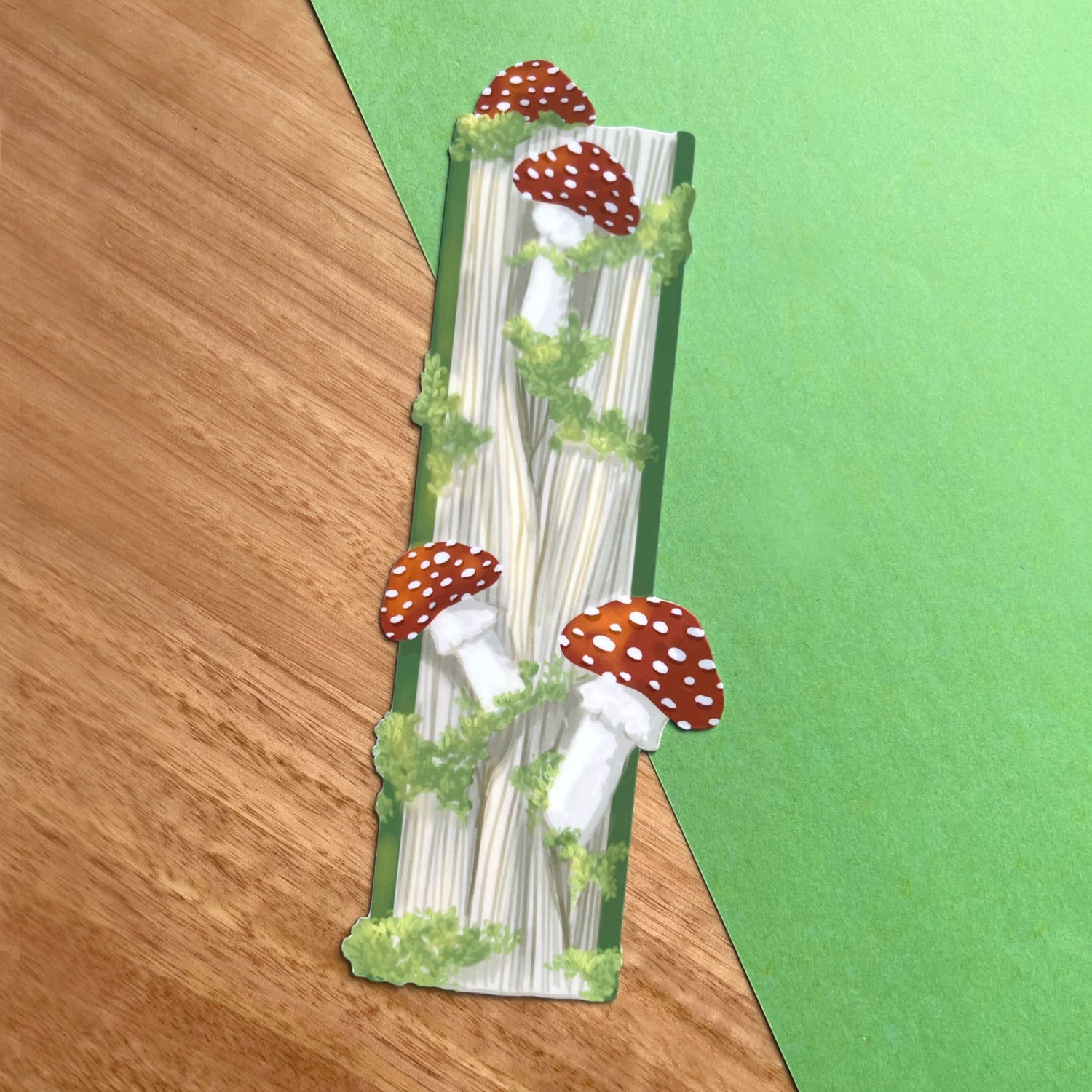 Glossy fantasy bookmark featuring a closed book with mushrooms and moss growing from the pages