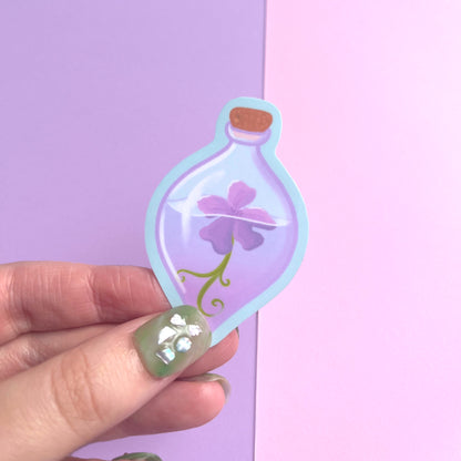 Enchanted fantasy vinyl sticker featuring a purple flower inside a clear potion bottle with violet water