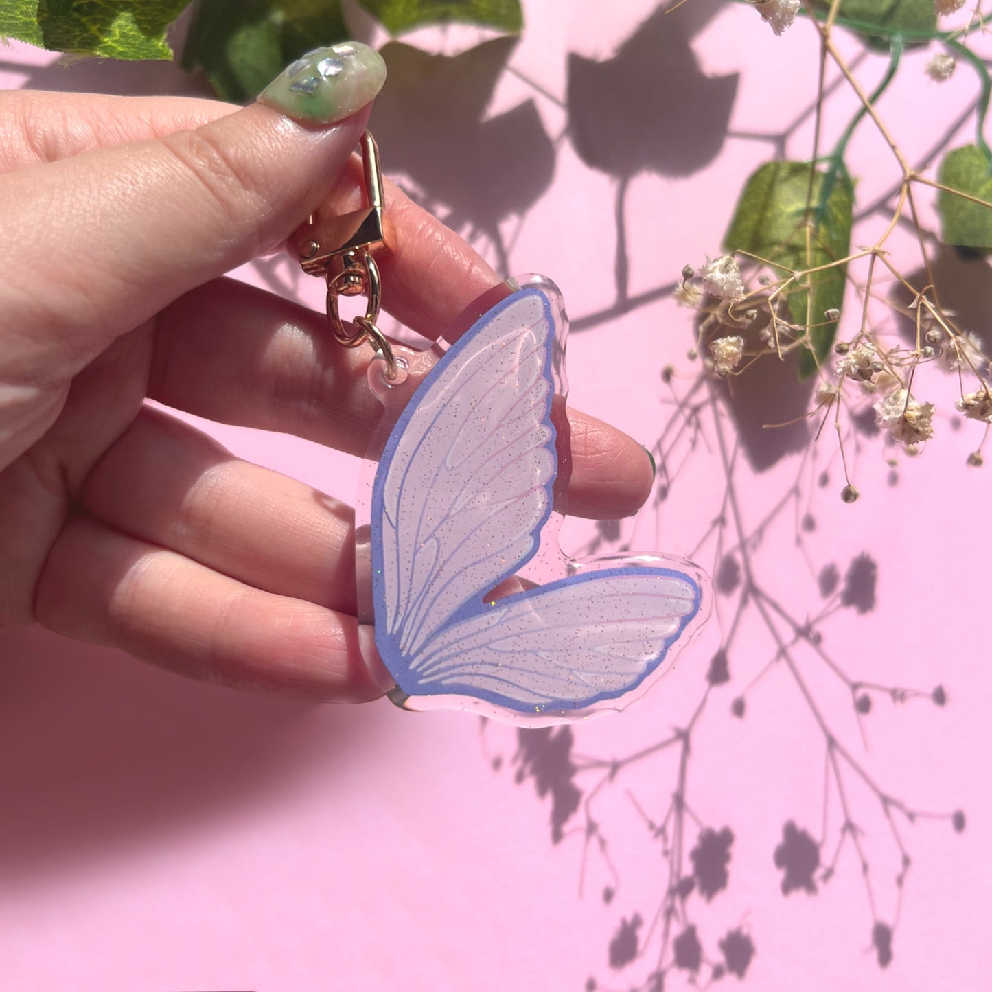 Close-up of acrylic fairy wing keychain showing pink purple wing details and gold clasp
