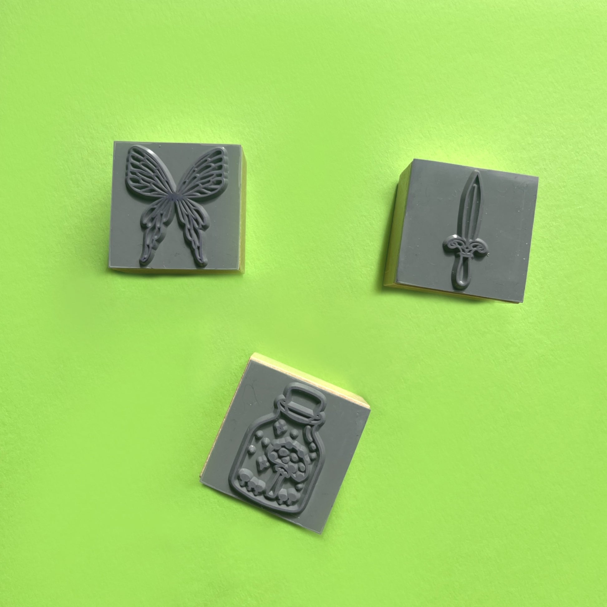 Close-up of fantasy rubber stamps showing fairy wings sword and mushroom in jar details
