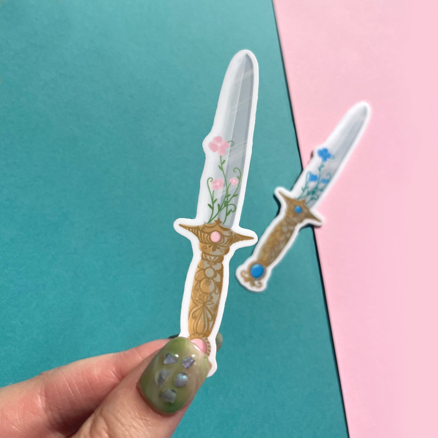 Close-up of pink and blue fantasy sword vinyl stickers showing floral and gemstone details