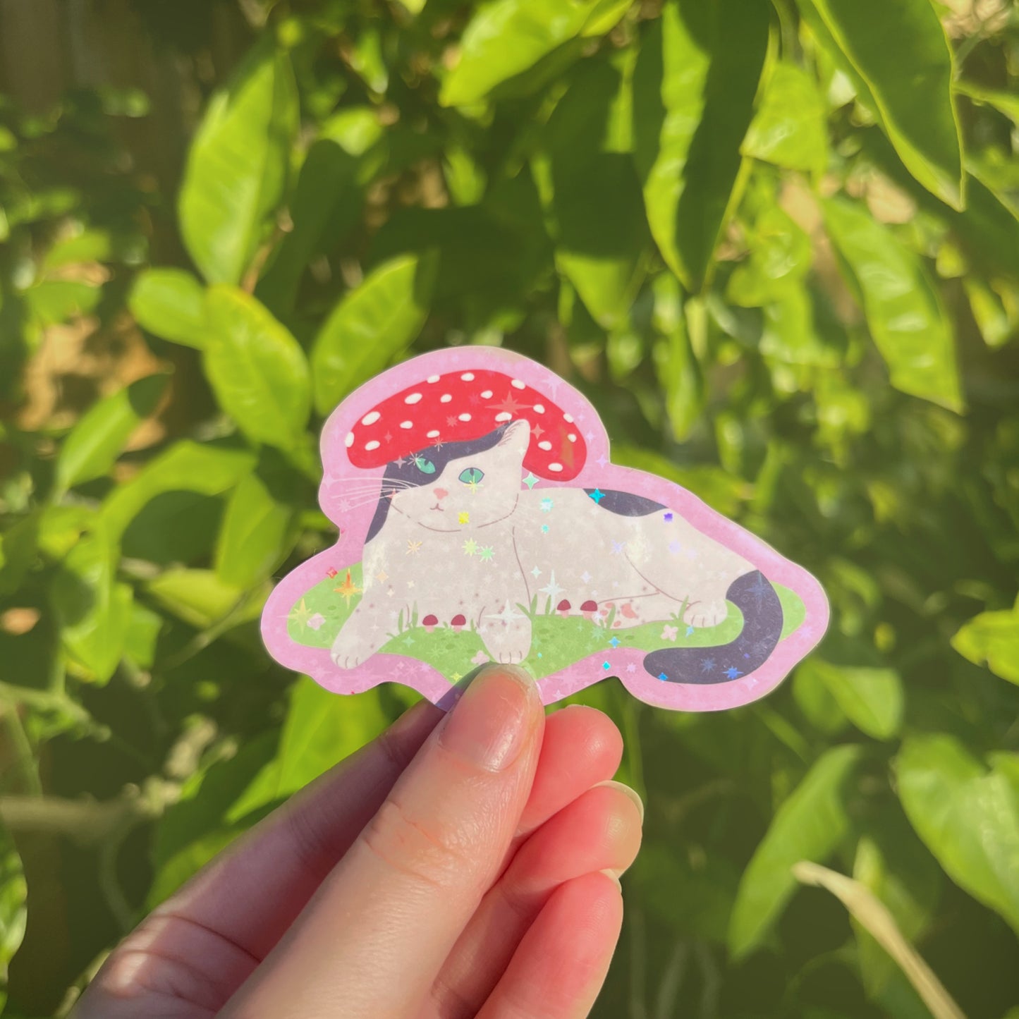 Close-up of holographic Mushroom Cat vinyl sticker showing sparkling finish and whimsical details