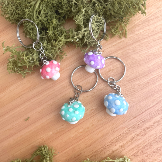 Handmade polymer clay mushroom keychains in red, blue, green, and purple – whimsical cottagecore charm for keys, bags, or gifts