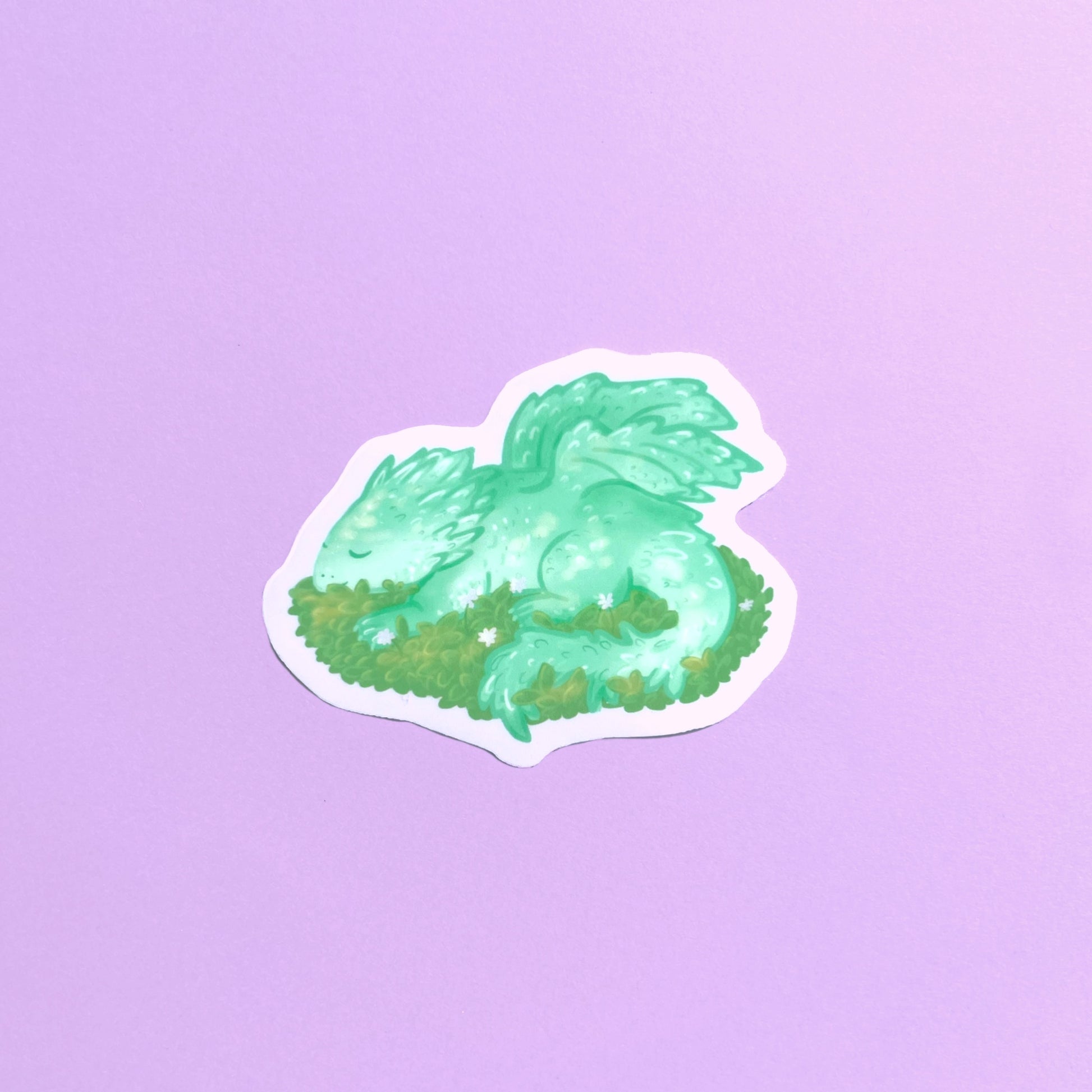 Sleeping baby dragon vinyl sticker with light green dragon resting on leaves